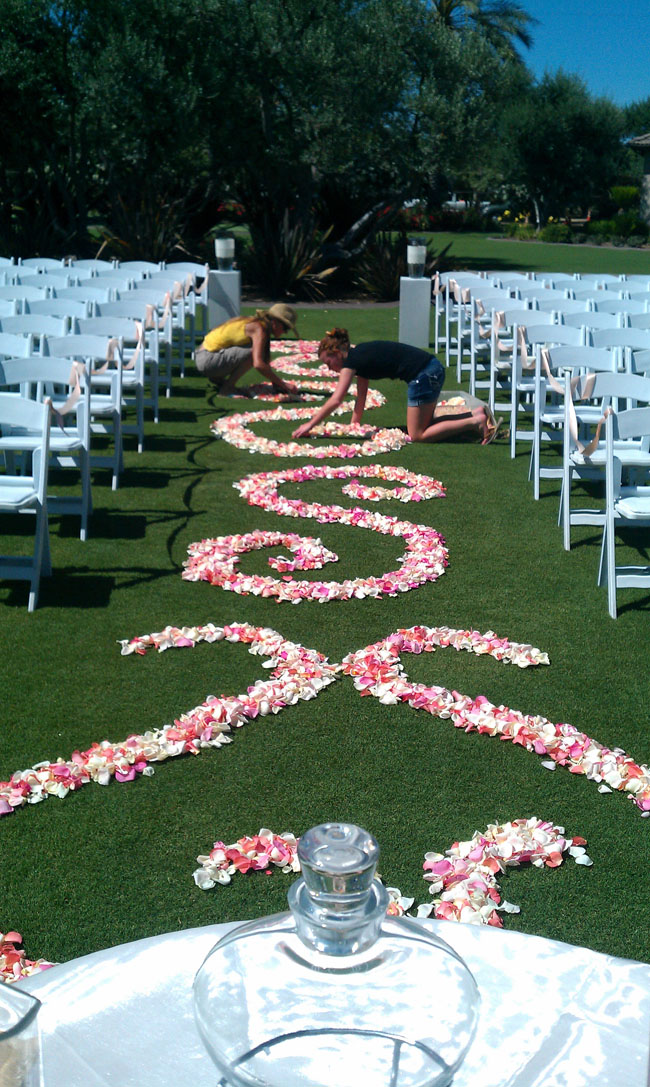 Designed by Fleurie Flowers, setting up the wedding ceremony aisle with rose petal scrolls