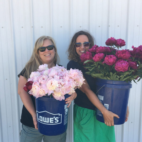 Alicia Schwede and Robyn Rissman holding buckets of Peonies for the Field to Vase Dinner