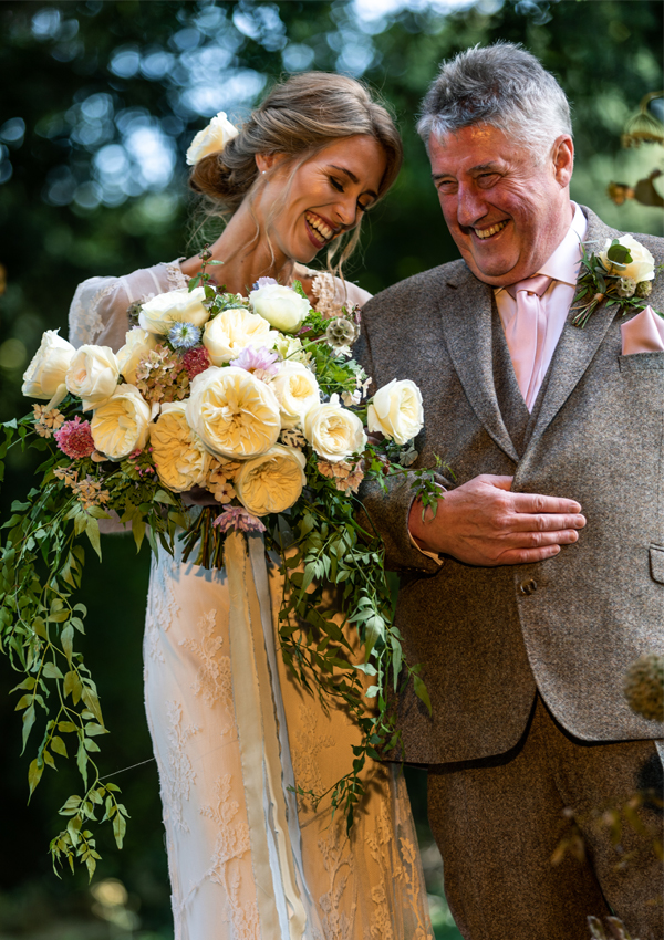 A touching moment between father and daughter as they walk to church, arm in arm. A very proud dad and a beautiful bride holding an exquisite bouquet of Ella (Auswagsy) roses complemented with seasonal flowers and foliage along with cascading jasmine trails. The hand-died silk ribbon had a beautiful softness in colour and was kept long to create added movement and romance.